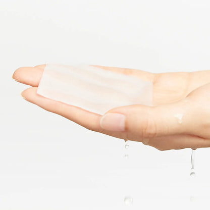 Hand holding a white patch with a small amount of liquid on a light gray background